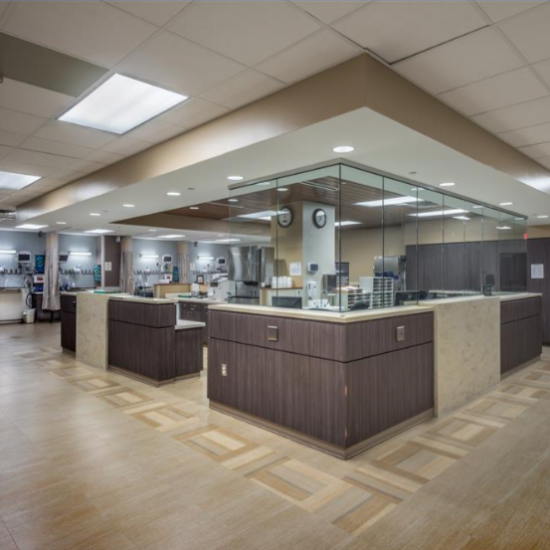 A modern hospital nurses’ station with sleek wood and glass panels highlights the work of a skilled commercial flooring company.