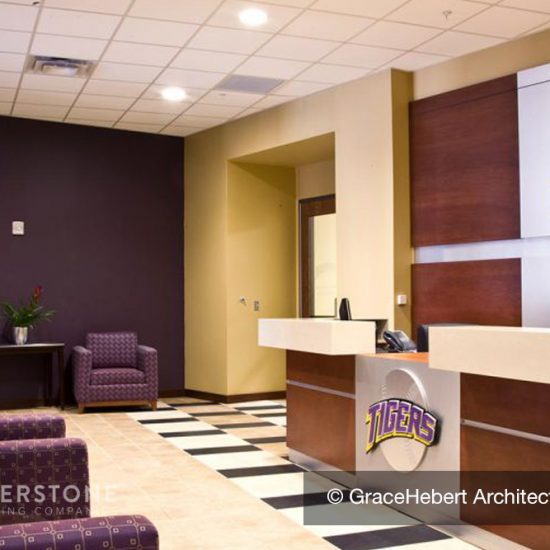 Reception area with LSU branding, purple chairs, and checkered flooring from a top flooring installation company, plus a large desk with “Tigers” logo.