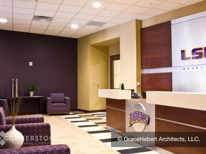 Reception area with LSU branding, purple chairs, and checkered flooring from a top flooring installation company, plus a large desk with “Tigers” logo.