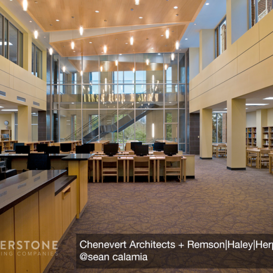 Spacious modern library interior with new flooring installation, high ceilings, large windows, bookshelves, and rows of computers on desks.