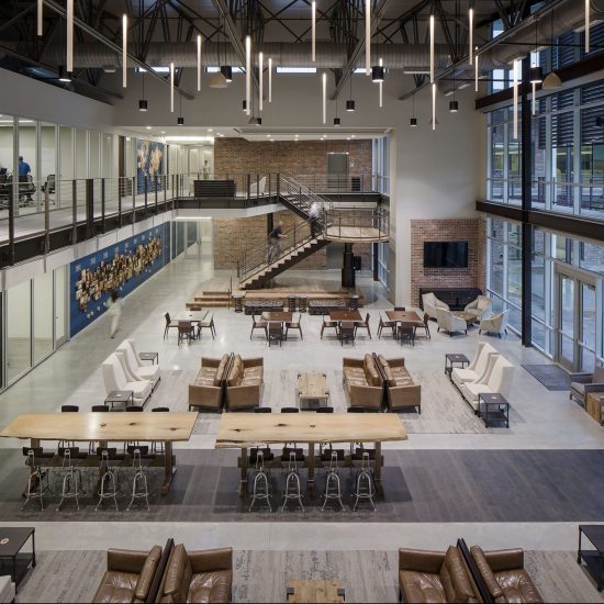Modern open-plan office with lounge seating, wooden tables, large windows, and expert finishes by a leading commercial flooring company.