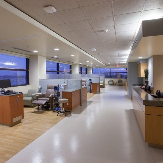 A modern hospital treatment area with patient chairs and medical equipment features floors by a leading commercial flooring company at Ochsner Cancer Institute.