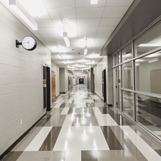 Empty, brightly lit hallway in a school or office building showcases new flooring installation by a professional flooring installation company.