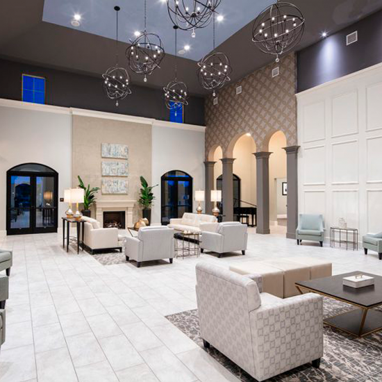 Spacious modern lounge with sofas, chandeliers, decorative walls, large windows, and tiled flooring by an expert flooring installation company.