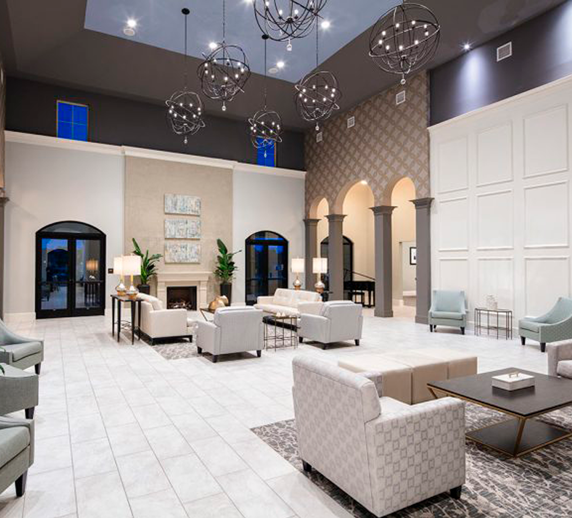 Spacious modern lounge with sofas, chandeliers, decorative walls, large windows, and tiled flooring by an expert flooring installation company.