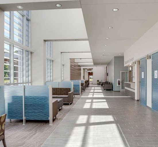 A bright hospital waiting area with seating booths, tables, large windows, and new flooring installation from a commercial flooring company.