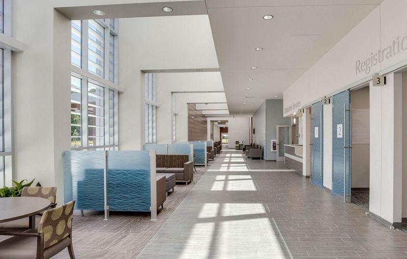 A bright hospital waiting area with seating booths, tables, large windows, and new flooring installation from a commercial flooring company.