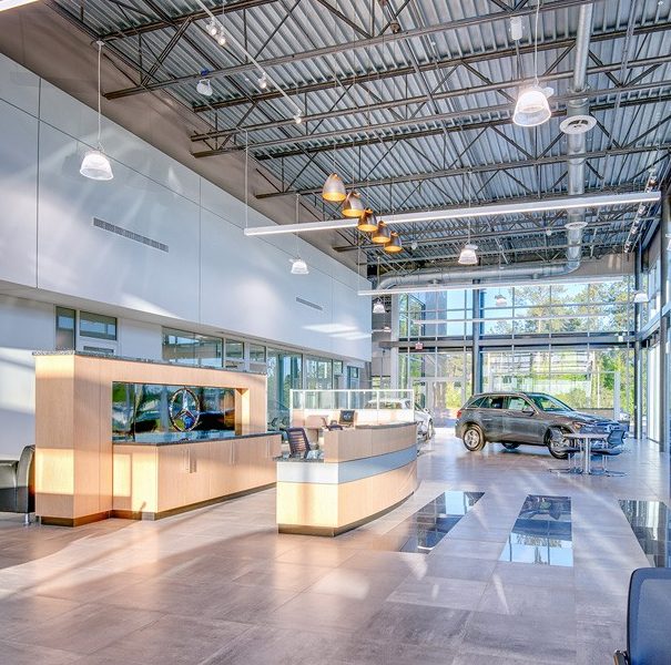 A modern car dealership showroom with sleek flooring installed by a professional flooring contractor, plus a reception desk and glass walls.