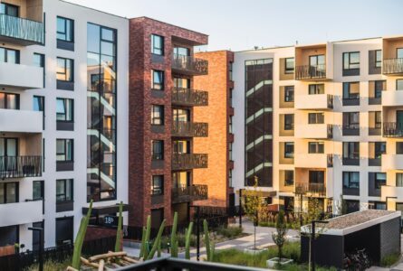 Modern apartment buildings with balconies and large windows surround a courtyard designed by a leading flooring installation company.